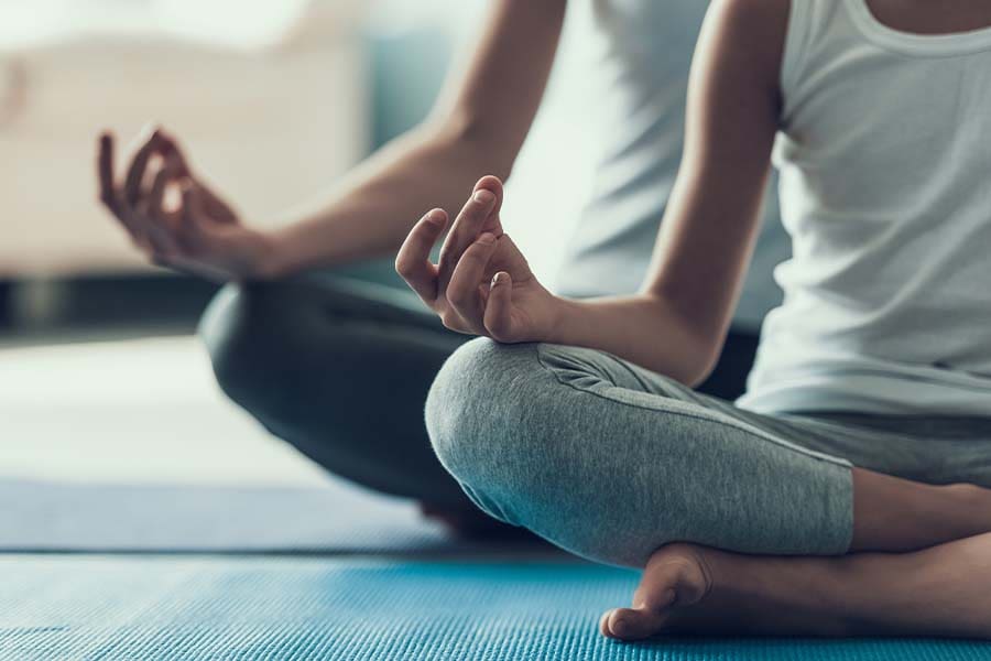 Employee Benefits - Closeup Of a Young Woman and Her Daughter Doing Yoga Pose in Their Living Room While Sitting on Yoga Mats